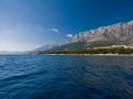 Blick auf den Strand von Makarska vom Meer. Das kristallklare Wasser ist frei von jeglicher Verschmitzung oder Algen.